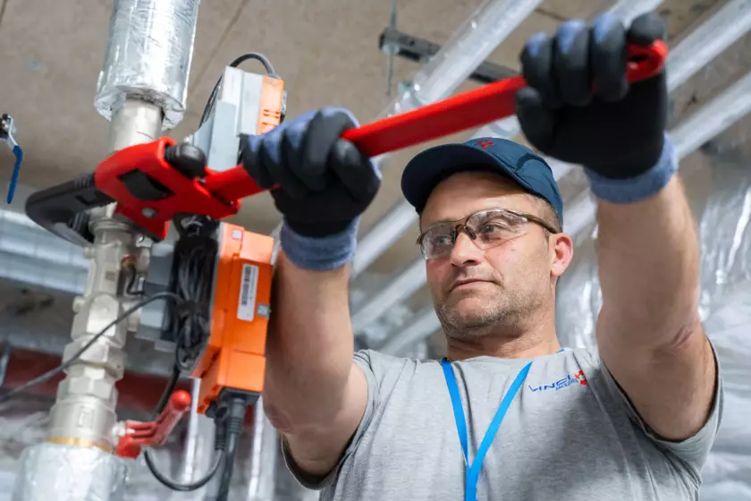 Photographie de reportage réalisée par Bertrand Perret montrant un salarié de Vinci facilities en train de serrer un boulon sur une pièce métallique