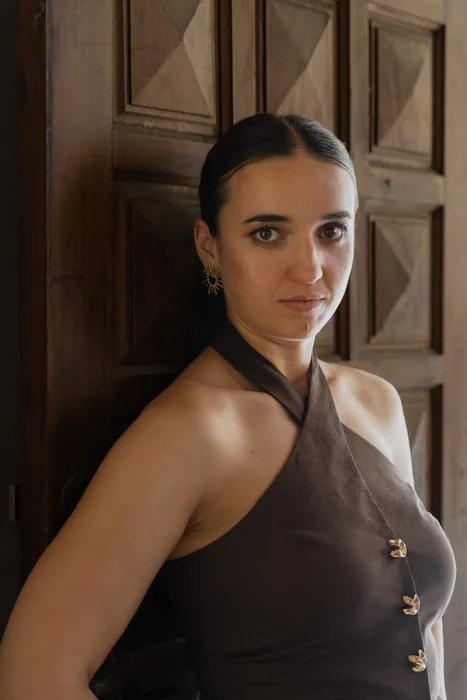 Photographie d'une jeune femme en lumière mixte (naturelle + flash) dans un environnement existant (dos à une porte)
